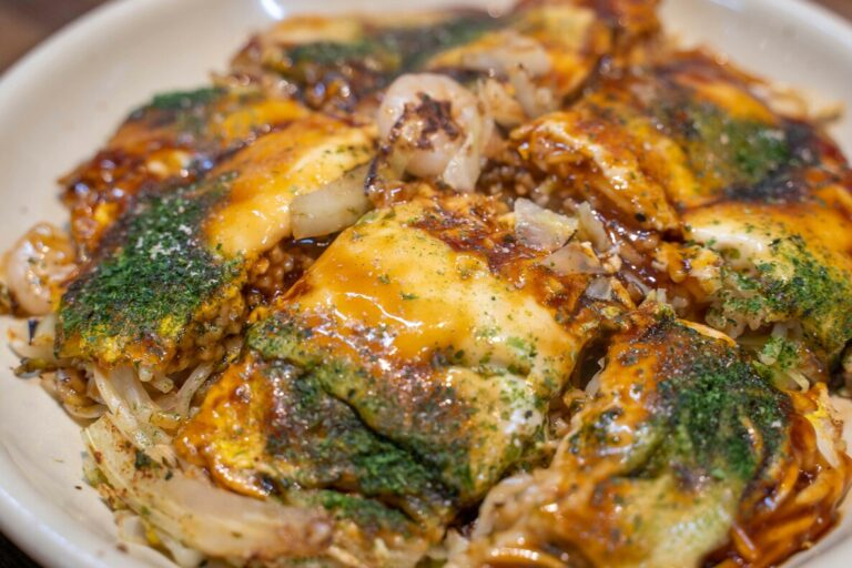 Japanese Food in Singapore : A close-up of sizzling okonomiyaki topped with bonito flakes and drizzled with mayo.