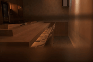 Minimalist omakase counter, featuring a warm wood bar with sleek white chairs under ambient lighting. The intimate setting evokes quiet anticipation, inviting guests into a curated chef’s choice experience rooted in precision, seasonality, and trust.