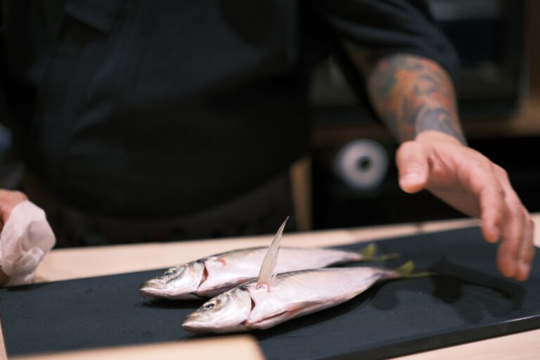 Chef Masa carefully preparing fresh, premium-grade fish at the sushi counter, showcasing the precision and artistry behind an authentic omakase dining experience.