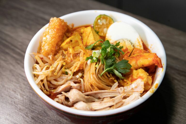 Restaurants in Singapore: A fragrant bowl of laksa topped with prawns, tofu puffs, and coconut broth, representing Singapore’s Peranakan flavours.