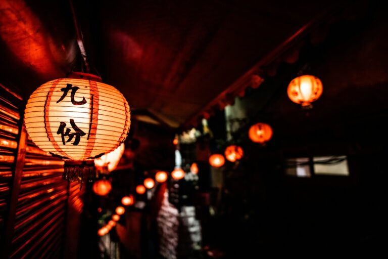 A soft glowing Japanese lantern hanging at the entrance of the restaurant, welcoming guests with its warm light and traditional charm