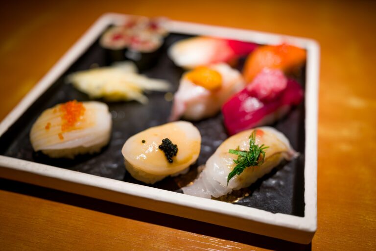 A traditional sushi placed fresh slices of fish, such as medium fatty tuna, atop seasoned sushi rice. The scene captures the artistry of Japanese cuisine, showcasing the chef's skill in creating this delicate dish for diners at a sushi restaurant.