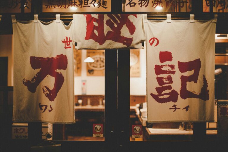 Japanese Food in SG : The exterior of a Japanese restaurant in Tokyo-style architecture, featuring wooden panels, lanterns, and a noren curtain welcoming diners inside.