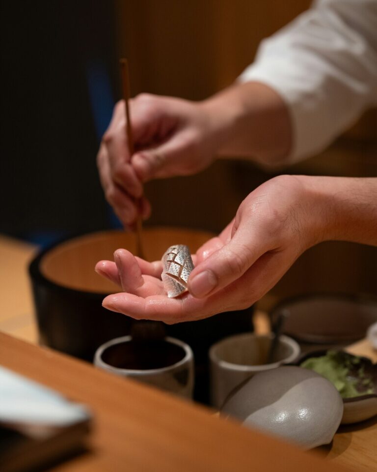 An omakase chef demonstrating Japanese culinary arts, showcasing refined knife skills, delicate plating techniques, and premium seasonal ingredients.