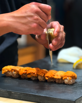 Chef Masa expertly shaping sushi behind the counter, focusing on his precise hand movements and dedication to creating an authentic omakase experience.