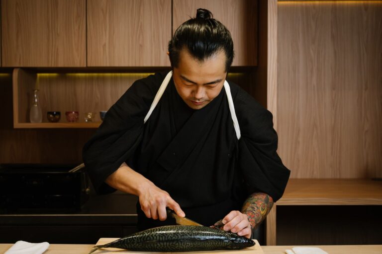 Chef Masa delicately slices fresh fish at the counter, showcasing precise omakase craftsmanship in an intimate dining setting at Sushi Masa by Ki-Setsu.