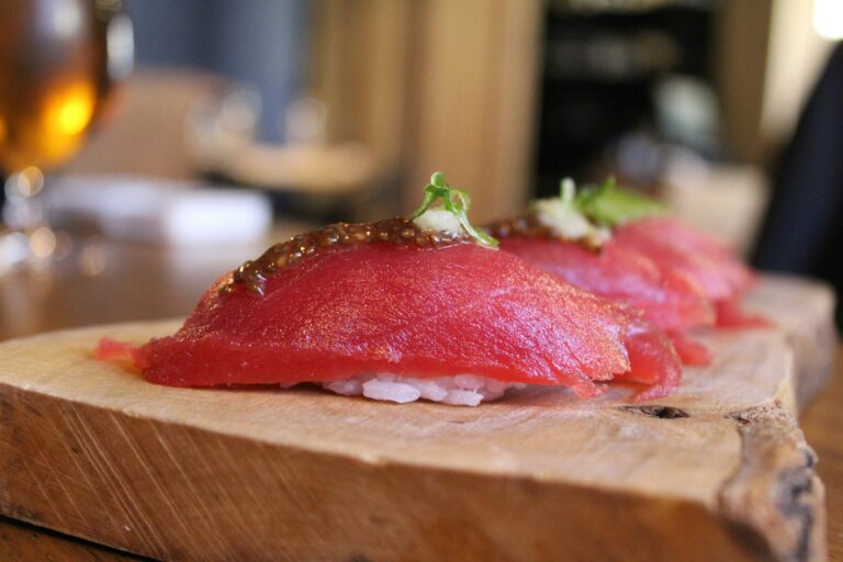 The image showcases fresh sushi ingredients, including vibrant vegetables and seafood, artfully arranged on a wooden counter, accompanied by traditional Japanese knives. This culinary adventure highlights the finest ingredients, reminiscent of the authentic flavors found in Singapore's award-winning restaurants.