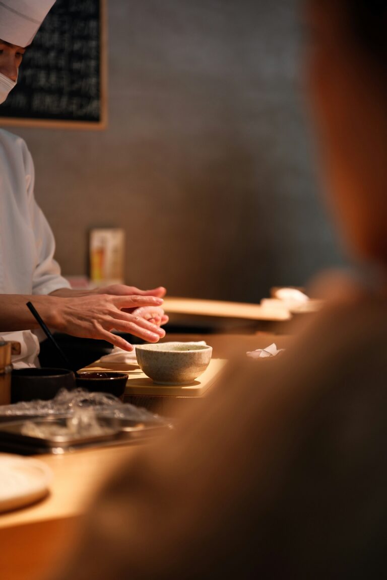 A chef preparing sushi during an omakase session, carefully shaping the rice and placing fresh fish with precision for a personalised dining experience.