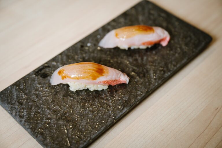 Two beautifully crafted sushi pieces sit on the table, showcasing clean presentation and balanced textures in minimalist Japanese style.