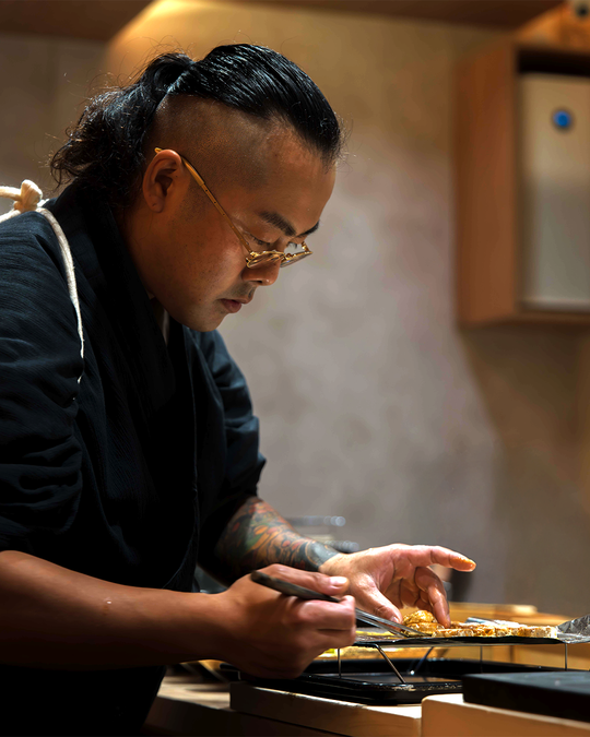 Chef Masa carefully shaping a piece of sushi at the omakase counter, his hands steady and focused, capturing the artistry, precision, and dedication behind every handcrafted bite at Sushi Masa.