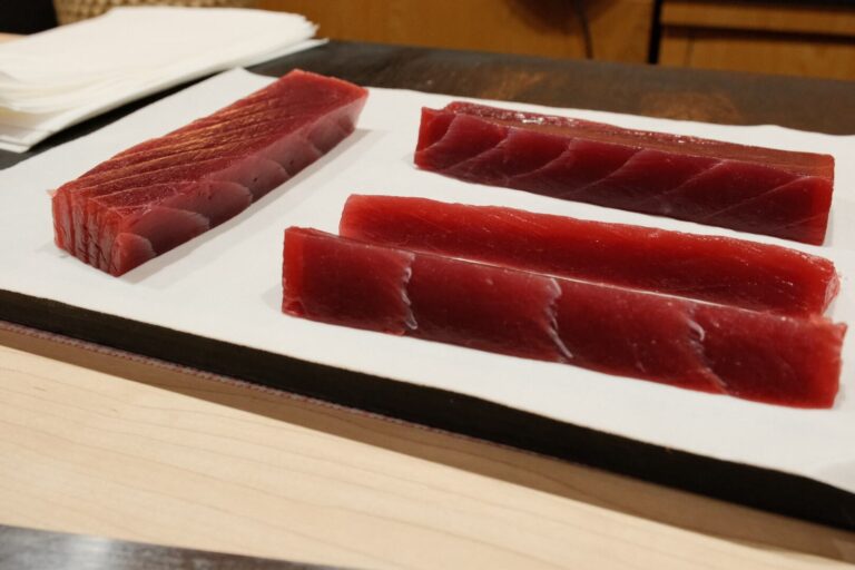 A focused chef preparing sushi behind the counter, illustrating how rushed dining can interrupt the slow, intentional rhythm of a traditional omakase experience.
