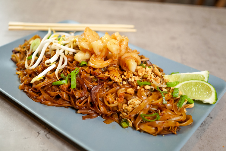 A steaming plate of Char Kway Teow, featuring flat rice noodles stir-fried with fresh prawns, cockles, bean sprouts and Chinese chives, glistening with smoky wok hei and rich savoury sauce