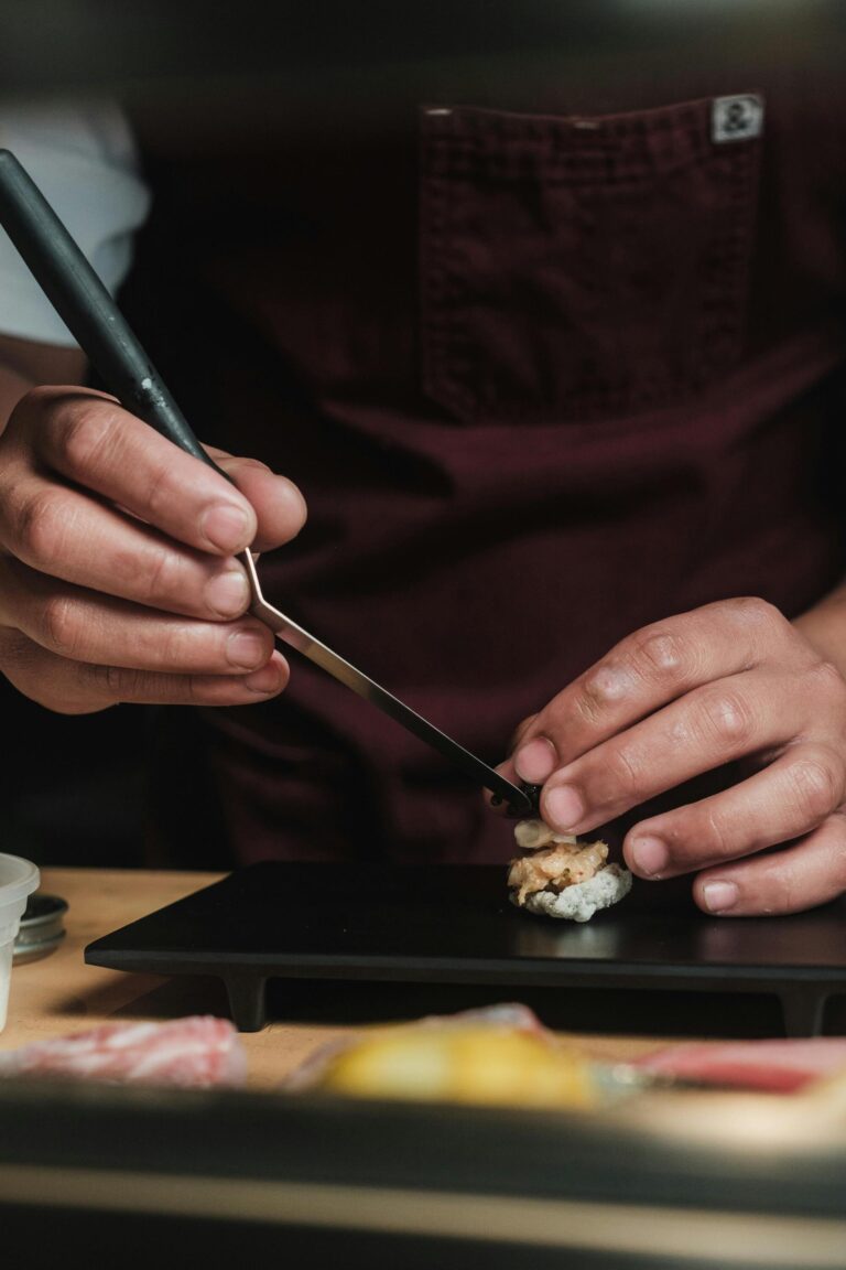 A sushi chef skillfully preparing a delicate sushi piece at the counter, capturing the artistry and focus behind an authentic omakase experience.
