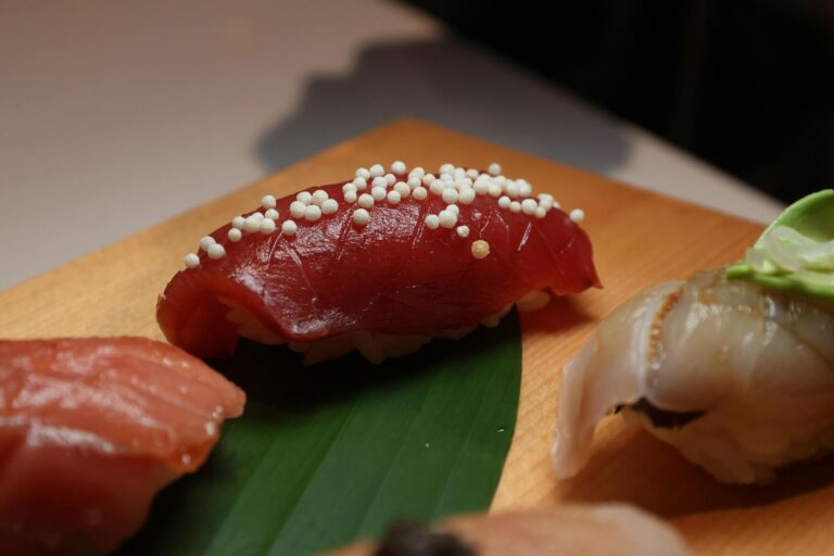 A close view of traditional Edomae-style sushi, showcasing fresh, glistening cuts of fish placed delicately on vinegared rice, highlighting the craftsmanship of classic Japanese sushi.