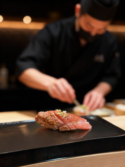The image depicts an elegant sushi at counter setup in an omakase restaurant, highlighting the intimate relationship between the chef and diners as they enjoy a carefully curated lunch omakase menu featuring seasonal fish and signature dishes. The ambiance reflects a dedication to quality and freshness, creating a memorable dining experience.