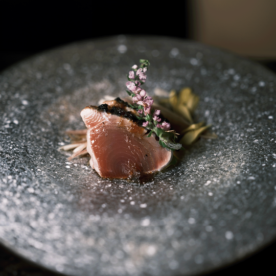 A refined omakase setting with a chef serving diners directly at the counter, emphasising exclusivity, craftsmanship, and curated seasonal dishes.