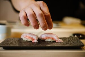A chef delicately sprinkles fine salt over freshly prepared sushi, enhancing its natural flavours