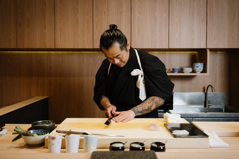 A skilled chef carefully slicing fresh fish with a razor-sharp blade, showcasing years of discipline, precision, and respect for the ingredient.
