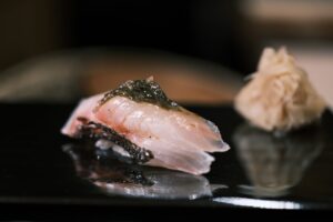 An exquisite piece of omakase sushi featuring fresh, glistening fish, ready to be savoured