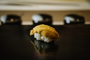 Fresh sea urchin sushi delicately placed on seasoned rice, showcasing its golden colour, creamy texture, and ocean-fresh quality typical of high-end omakase dining.