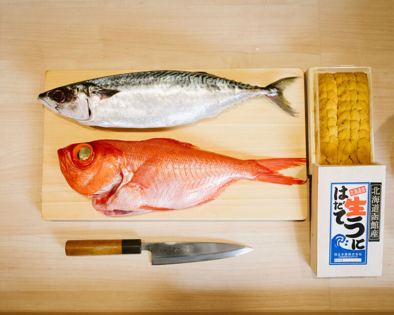 Selection of fresh fish and golden uni laid out on a clean surface, emphasising quality ingredients for sushi preparation.