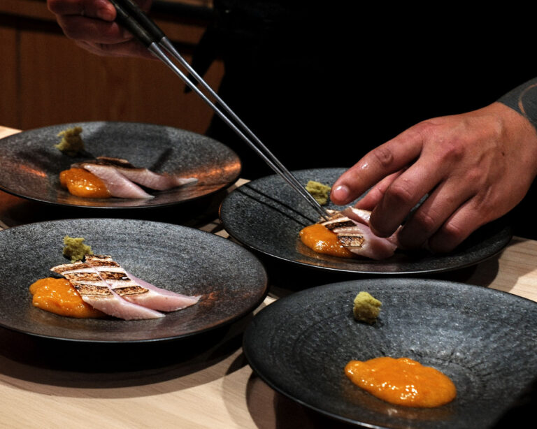 Chef Masa’s hands preparing an omakase dish, gently shaping ingredients with skilled movements, reflecting the attention to detail in traditional Japanese cuisine.