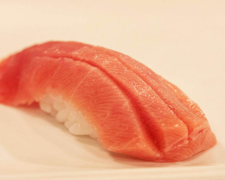 Edomae-style tuna sushi placed on seasoned rice, lightly brushed with soy-based sauce, reflecting traditional Japanese preparation that enhances the tuna’s umami flavour.