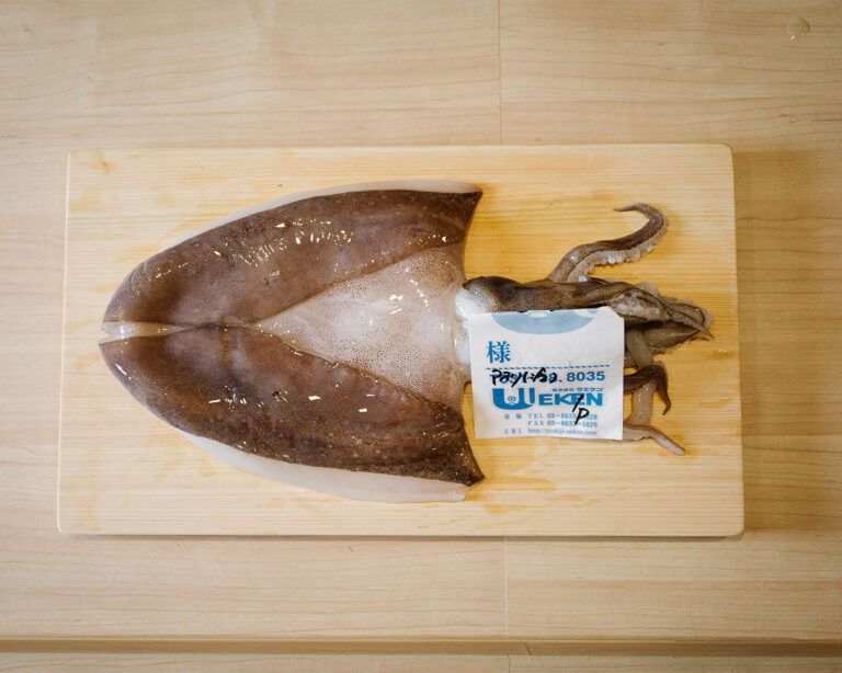 Whole fresh squid placed neatly on a preparation table, showing natural sheen and firm texture.