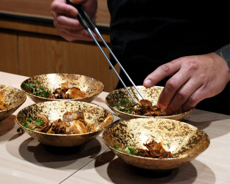 A chef preparing an omakase dish at the counter, focusing on careful plating and seasonal ingredients.