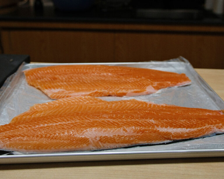 Evenly sliced salmon with visible marbling laid out on a cutting board, ready for sushi or sashimi.