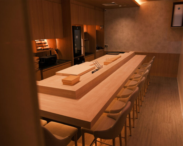 The sushi bar at Sushi Masa with neatly arranged ingredients and a minimalist design, reflecting a refined and authentic Japanese dining environment.