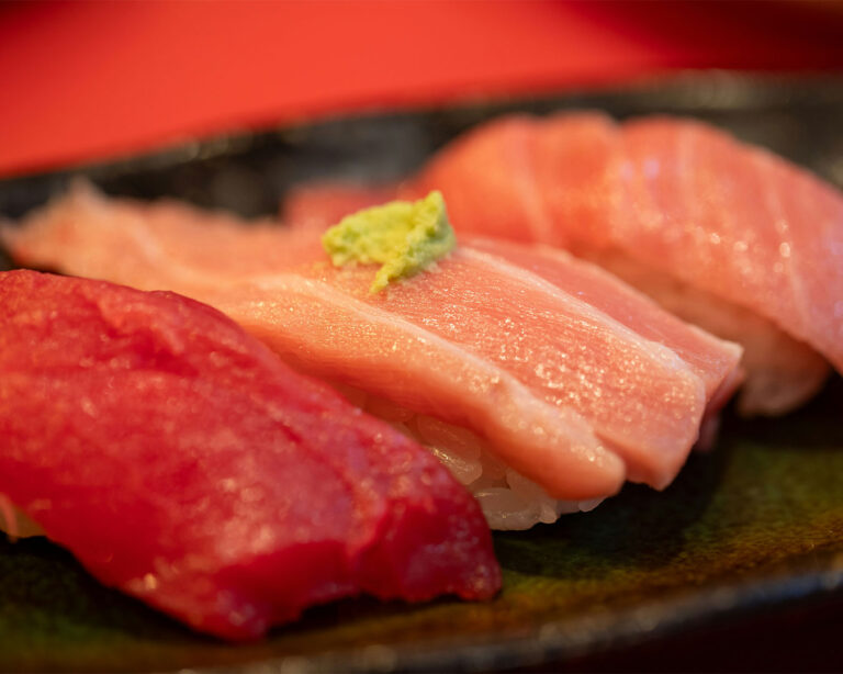 Fresh tuna sushi arranged on a clean plate, displaying vibrant red slices of tuna over compact rice, presented in a minimal and elegant style to emphasise freshness and quality.