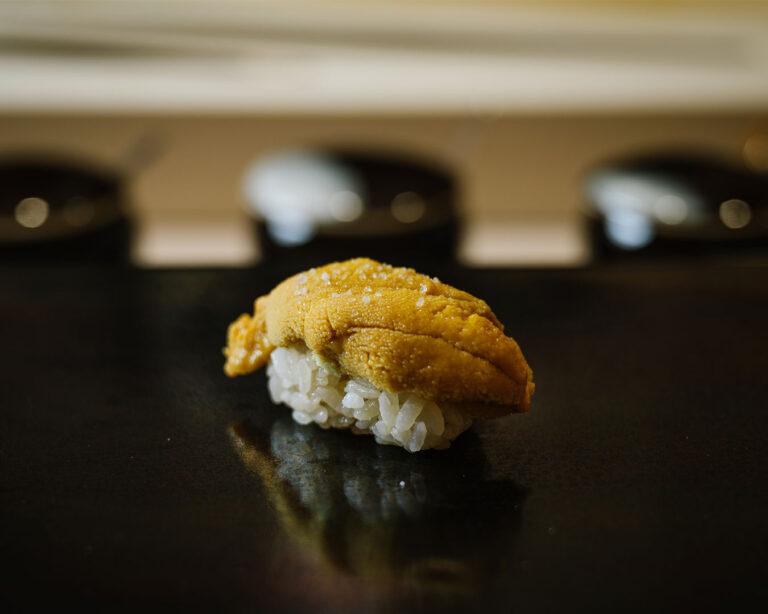 A piece of sea urchin roe sushi served elegantly on a plate, featuring a smooth, golden topping with a luxurious and refined appearance.
