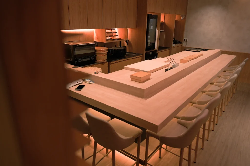 An empty, modern Japanese sushi counter with light wood finishes and minimalist interior design.