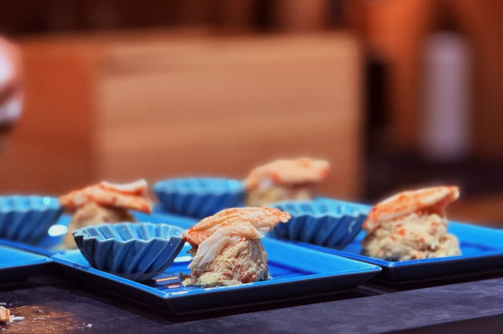 Blue plates showcasing gourmet crab dishes with vibrant shells and shredded crab meat. The setting is elegant, conveying a fine dining atmosphere.