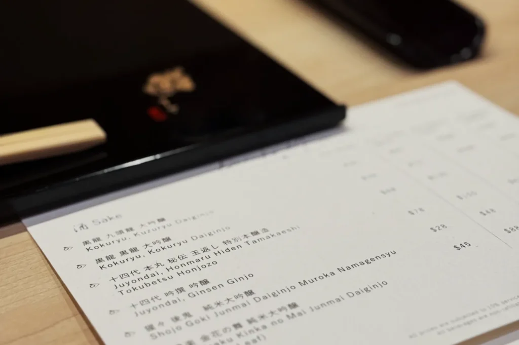 A menu placed on a wooden surface next to chopsticks.