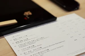 A menu placed on a wooden surface next to chopsticks.