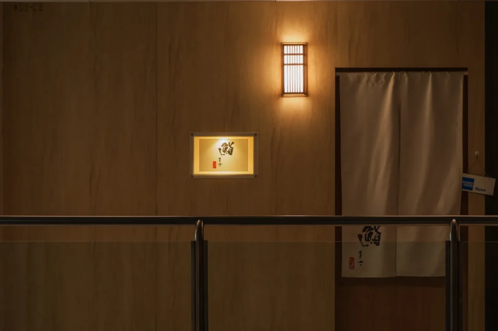 A softly lit wall with a decorative window and a curtain, suggesting an entrance to a room or establishment.