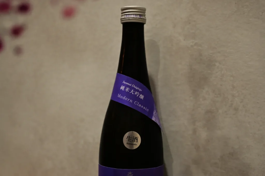 A bottle of sake with a dark label and a silver seal, titled "Junmai Daiginjo Modern Classic."