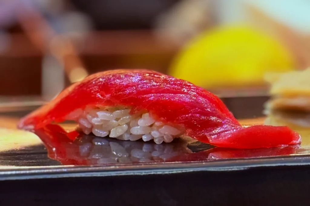 A piece of sushi topped with thinly sliced red tuna on a bed of rice.