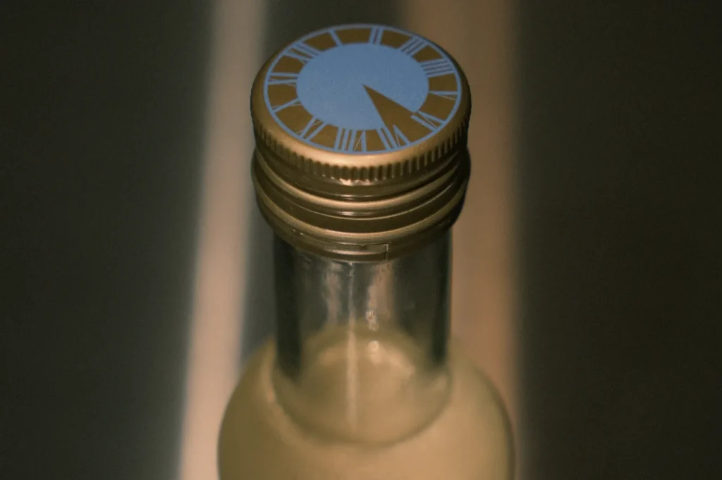 A close-up of a bottle cap with a decorative design featuring clock-like markings.