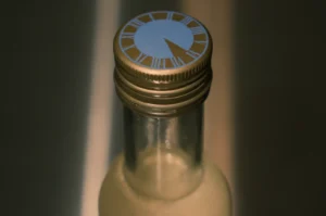 A close-up of a bottle cap with a decorative design featuring clock-like markings.