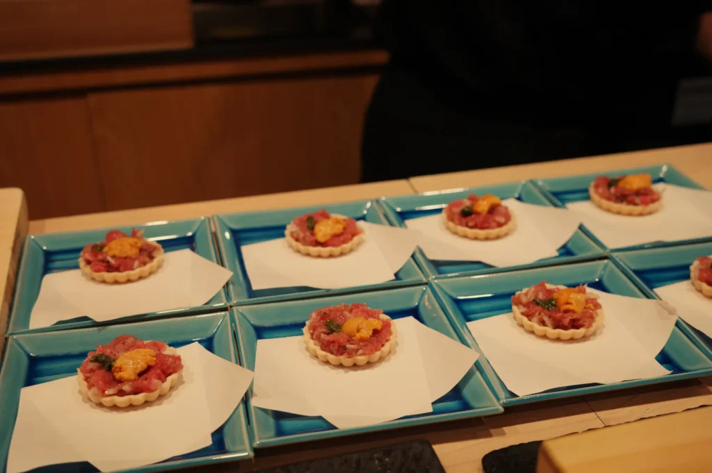 A display of chopped fatty tuna topped with colorful ingredients, arranged on blue plates.