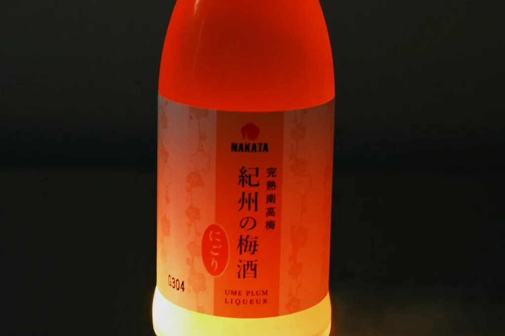 A bottle of ume plum liqueur with a label in Japanese, illuminated from behind.