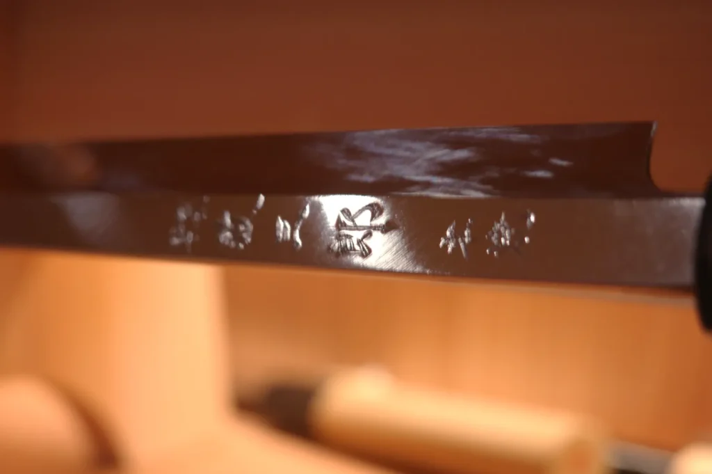 A close-up of a knife blade with intricate markings and a shiny surface.