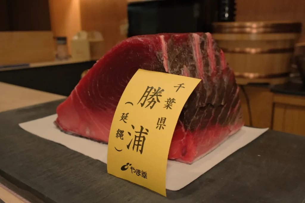 A large piece of tuna with a yellow label displaying text in Japanese.
