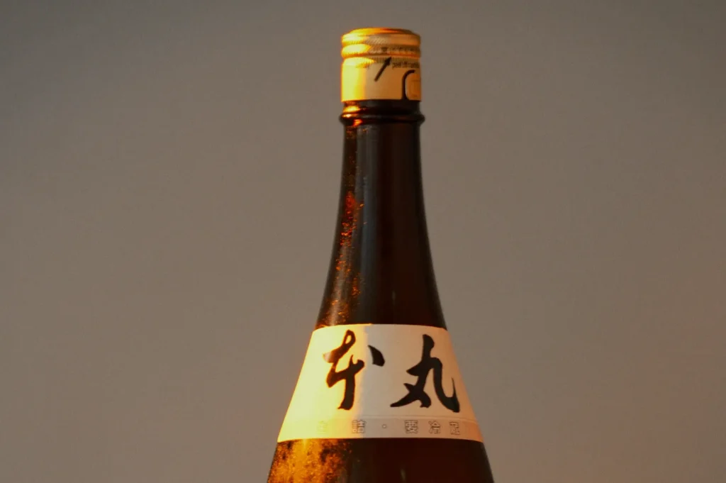 A close-up of a sake bottle with a label featuring Japanese characters.