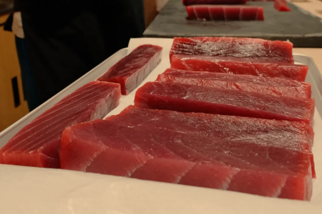 Pieces of raw tuna displayed on a tray, showcasing various cuts and textures of the fish.