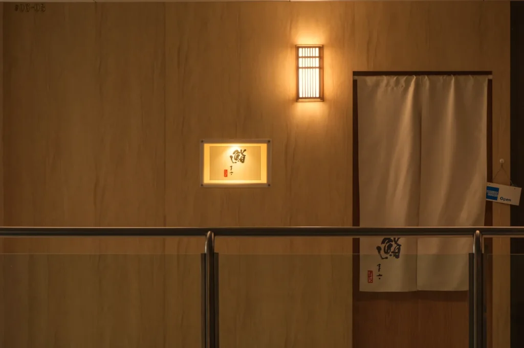 A well-lit wall with a light fixture, a small illuminated display case, and a white curtain.