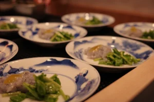 A set of plates featuring a dish with small portions of food, including a green vegetable and a smear of a sauce or puree, arranged aesthetically.